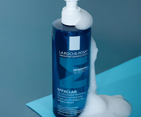 A bottle of La Roche-Posay facewash on a blue background, with bubbles running down the side of the bottle.