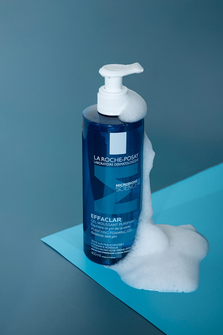A bottle of La Roche-Posay facewash on a blue background, with bubbles running down the side of the bottle.
