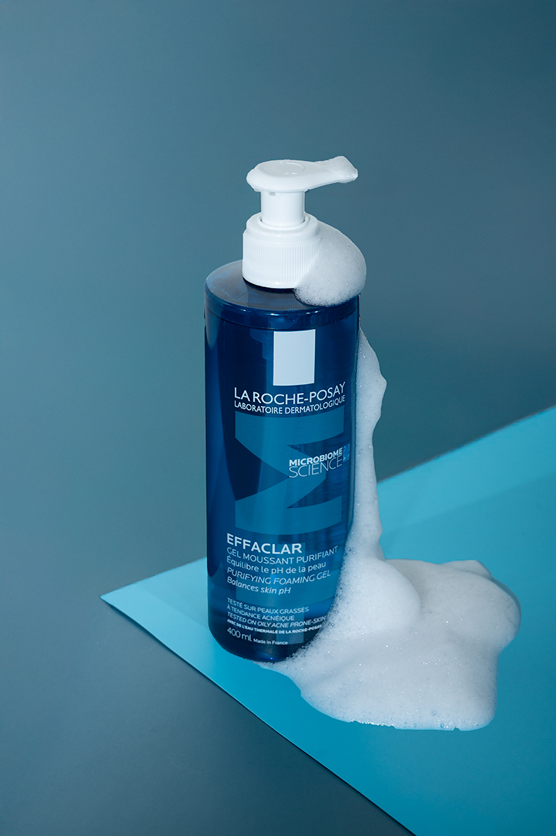 A bottle of La Roche-Posay facewash on a blue background, with bubbles running down the side of the bottle.